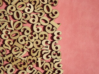 wooden numbers are randomly arranged on pink suede. High quality photo