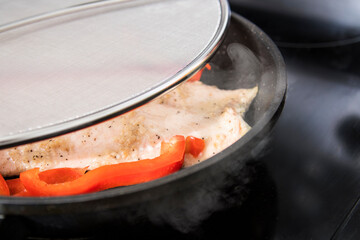 grilled chicken with seasoning in frying pan covered in splatter screen close up detail