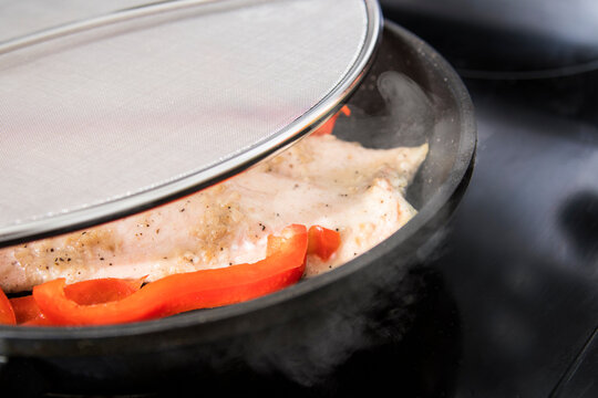 grilled chicken with seasoning in frying pan covered in splatter screen close up detail