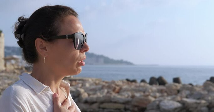 Woman with deep breath on beach. A stressed woman in sunglasses use an inhaler on the shore because of her asthma problems.