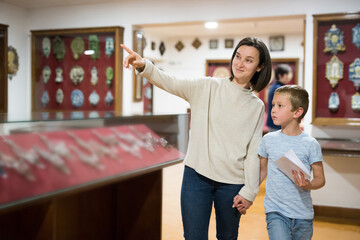 Smiling woman with school age son visiting museum together pointing to something interesting