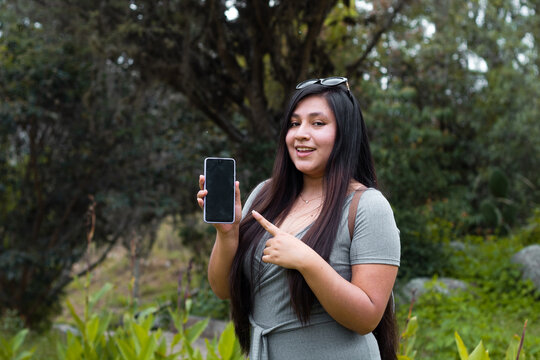 Chica mostrando la pantalla del tel&eacute;fono celular con la mano ,indicar,si,acepto,naturaleza,guau,