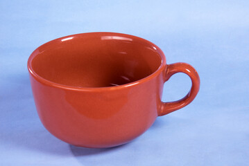 clay brown color porcelain cup with handle isolated on light blue background