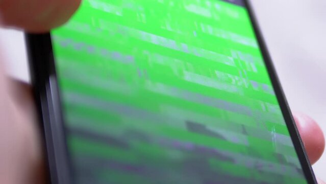 Person Watches a Video with a Distortion, Glitches on Smartphone Screen. Satellite digital signal transmission error, purple, green stripes, pixel noise, interference. Technical problem, off internet.