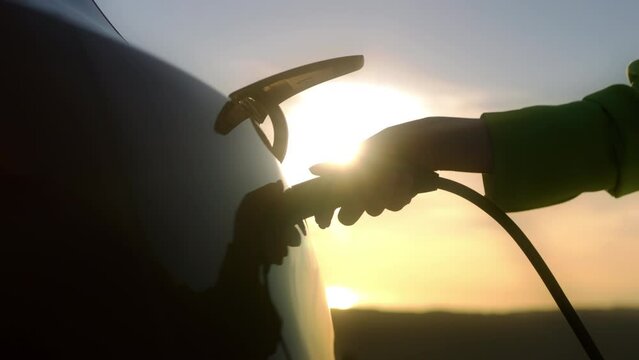 Slow motion close up woman plugging in power cable zero emission electric car