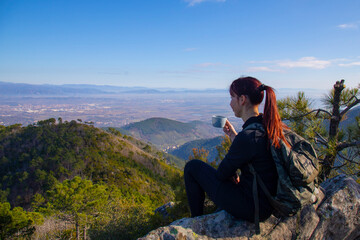 Naklejka premium Tracker woman on top of the mountain drinks a hot drink from a thermos