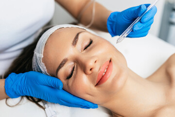 Obraz na płótnie Canvas Beautiful middle-aged woman enjoys a skin rejuvenation treatment at a beauty salon.