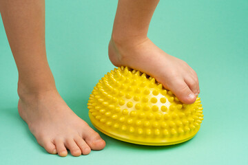 children's feet with a yellow balancer on a light green background, treatment and prevention of...