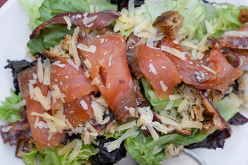 Caesar salad. Top view of a fresh Caesar salad with lettuce, parmesan cheese, bread croutons, smoked salmon, bacon and Caesar dressing.