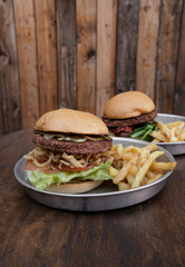 Vegetarian cuisine. Plant based burgers. NotCo Burgers. Closeup view of two NotCo hamburgers in metal dishes on the restaurant wooden table. 