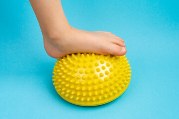 children's feet with a yellow balancer on a light blue background, treatment and prevention of flat...