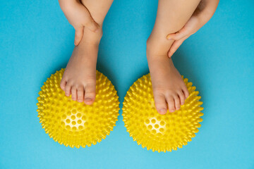 children's feet with a yellow balancer on a light blue background, treatment and prevention of flat...