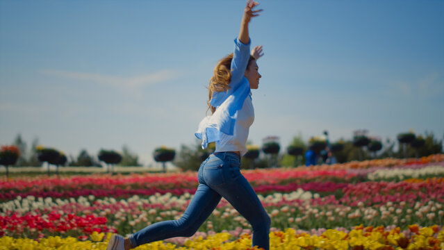 Happy woman profile running in flower garden in slow motion in spring sunny day.