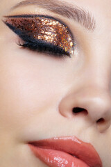 Close-up shot of female face with vogue golden shining eyes make