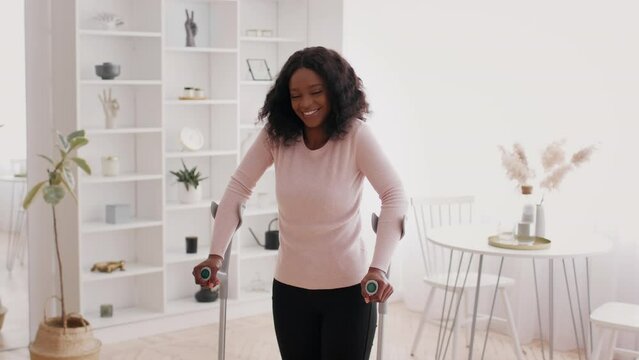 Cheerful Black Woman Standing With Crutches Posing At Home