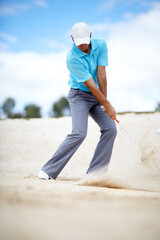 In the bunker. An image of a young male golfer chipping his ball out of a bunker in a game of golf.