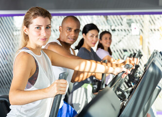 Athletic people running on elliptical trainer in a fitness club