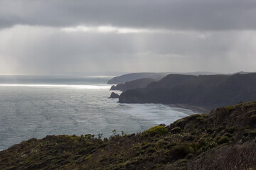 Panoramic view with cliffs, ocean and heavy clouds, North Island West Coast, New Zealand.