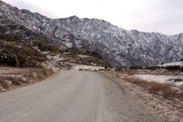 Low rock formation in the dried autumn hilly steppe under thunderclouds.