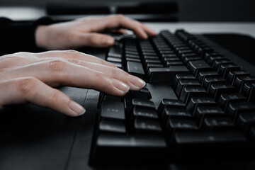 Close up image of woman hands typing on computer keyboard and surfing the internet on table.