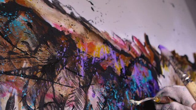Artist designer draws an eagle on the wall. Craftsman decorator paints a picture with acrylic oil color. Slow motion 180fps dark magic cinematic look. Painter painter dressed in a paint coat. Indoor.
