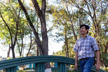 Hispanic man walking over a bridge in a park