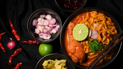 Khao Soi Kai in a black bowl served with side dish