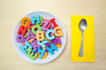 Large white porcelain soup bowl full of wood block letters in bright colors with A, B and C on top...