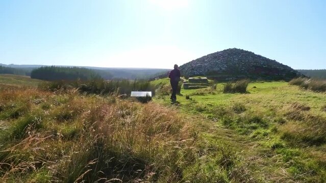 Visitor to the Grey Camster Chambered Cairns reads the notice board and moves towards the long cairn