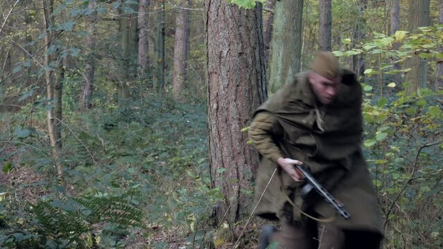 WW2 Soviet Russian red army soldier running with his machine gun through a forest in the second world war