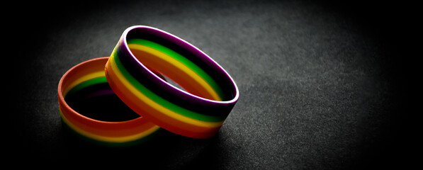 Rubber rainbow wristbands on black background, neon light edited, lgbt symbol, concept for lgbtq+ communities celebrations in pride month around the world.