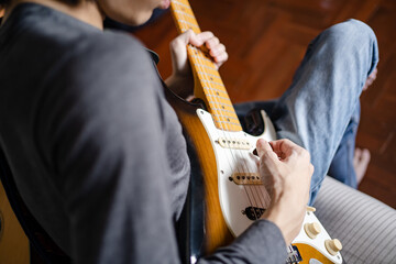 A man playing electric guitar on a bed