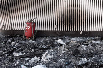 Destroyed building interior due to fire. Black burnt things after arson with red fire extinguisher.