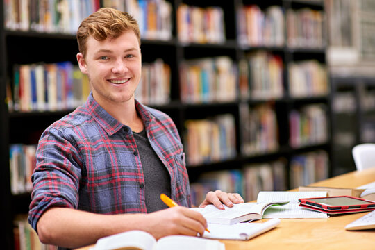 Hes top of his class. Portrait of a male student studying at a table in a university library.