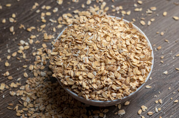 Dry oatmeal in a white plate on table on a wooden background. Top view.