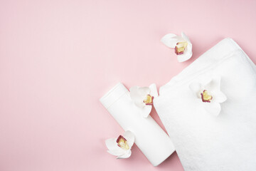 White bottle of shampoo and hair conditioner on a pink background with a towel and orchid flowers. Exotic aroma mockup bathroom with copy space.
