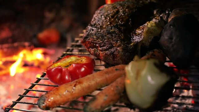 Close Up of meat and vegetables on the grill in the campsite. We can see the bonfire in the background. Lifestyle weekend activity shot. Cooking in the forest.