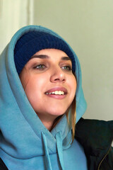Facial portrait of a young beautiful girl in a sweatshirt with a hood - 489136603