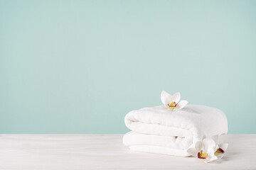 White towel and orchid flowers on a blue background with copy space.