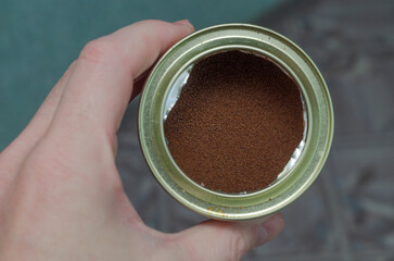 metal can in hand with instant coffee