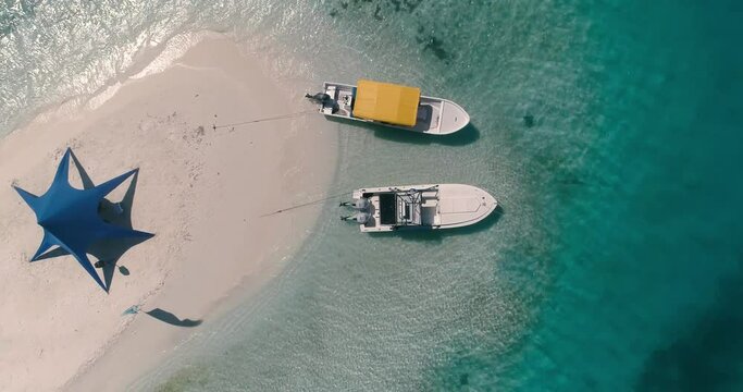 Drone turning above small boats and tent on sand beach in exotic island in los Roques