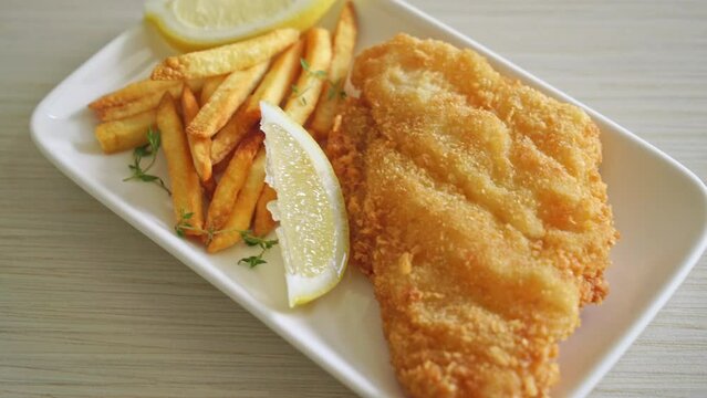 fish and chips - fried fish fillet with potatoes chips and lemon on white plate