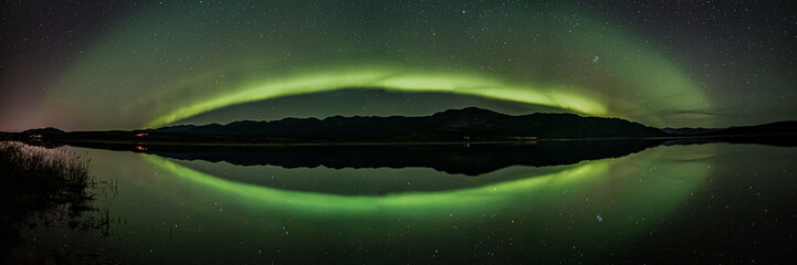 Ghostly northern lights scene in Yukon, Canada during fall with spectacular stars and green aurora borealis band across the northern landscape.  - obrazy, fototapety, plakaty
