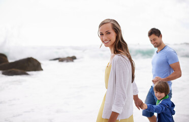 Taking in the beautiful scenery. Portrait of an attractive young woman walking along the beach with her family.
