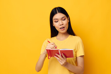 Charming young Asian woman with a notebook and pen in hand isolated background unaltered