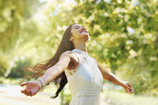 Carefree and full of joy. A carefree woman standing with her arms open in the park.