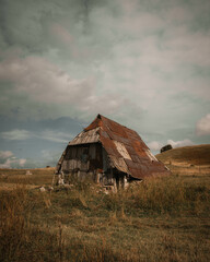 A scenic view of an old barn in the middle of a field in the countryside under a gloomy sky © Nermin Ribic/Wirestock