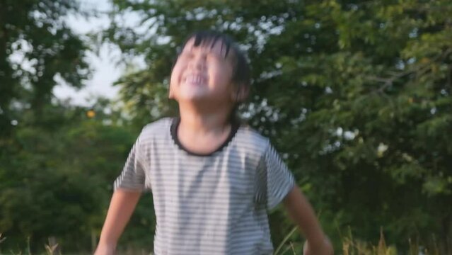 Happy Asian little girl covers her eyes while playing hide and seek in the park. Happy family doing activities together on holidays.