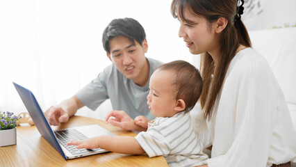 赤ちゃんにノートパソコンを見せる両親