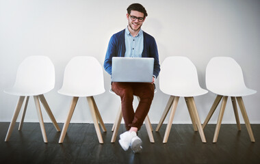 Im well prepared, thanks to the internet. Shot of a young businessman using a laptop while waiting in line.